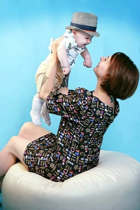Mamma che solleva il bambino con un cappellino