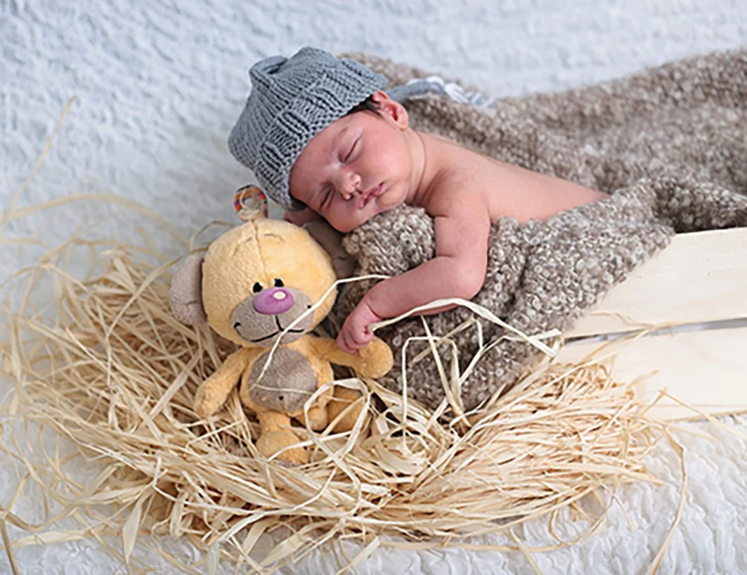 Neonato addormentato in un cestino con un peluche