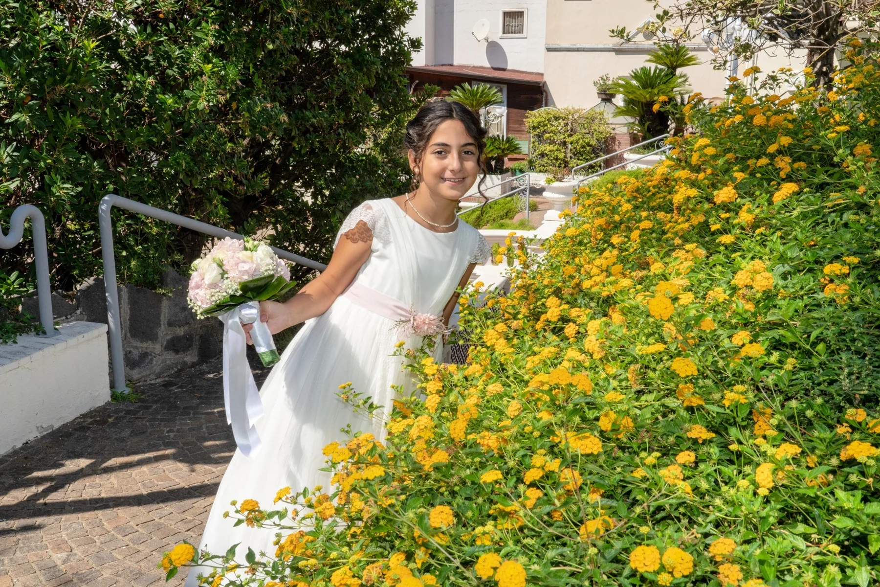 Ritratto di prima comunione accanto a fiori gialli