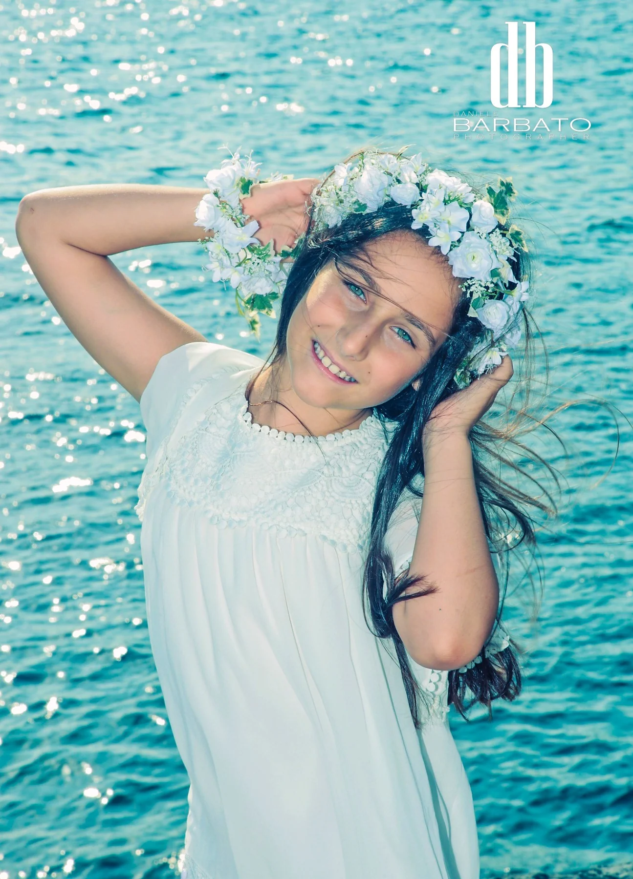 Bambina con coroncina di fiori vicino al mare